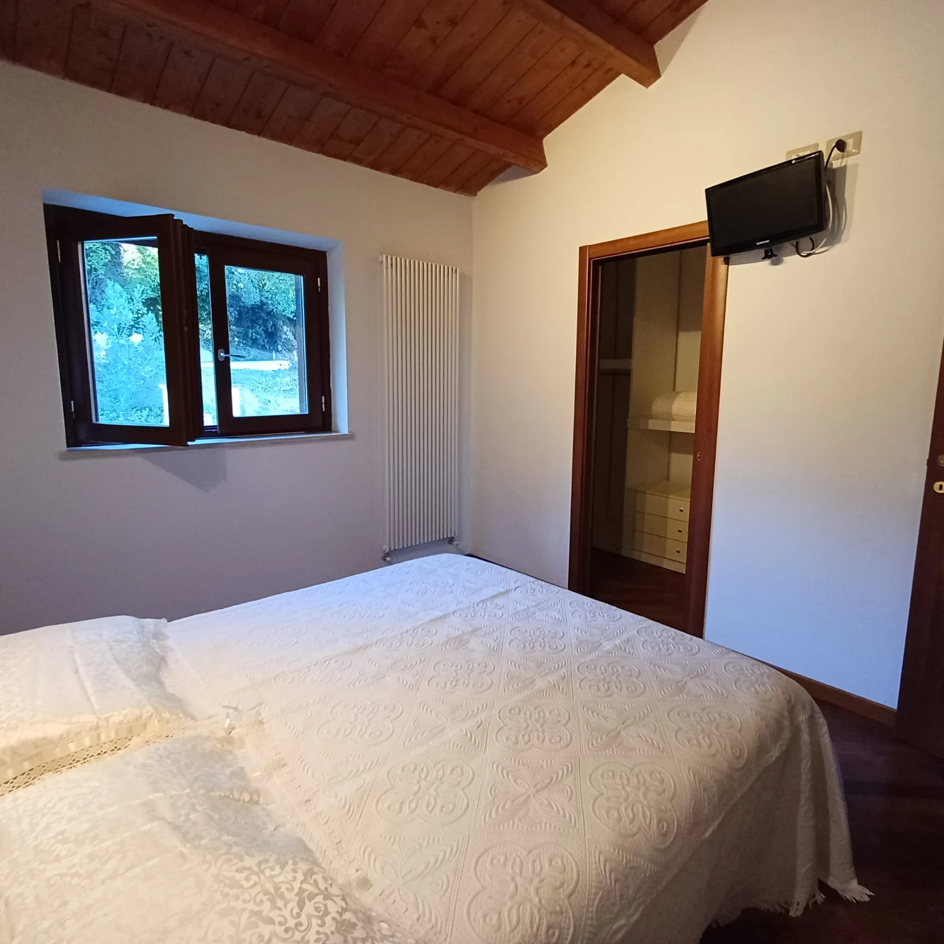 Camera matrimoniale con televisore, finestra e bagno adiacente