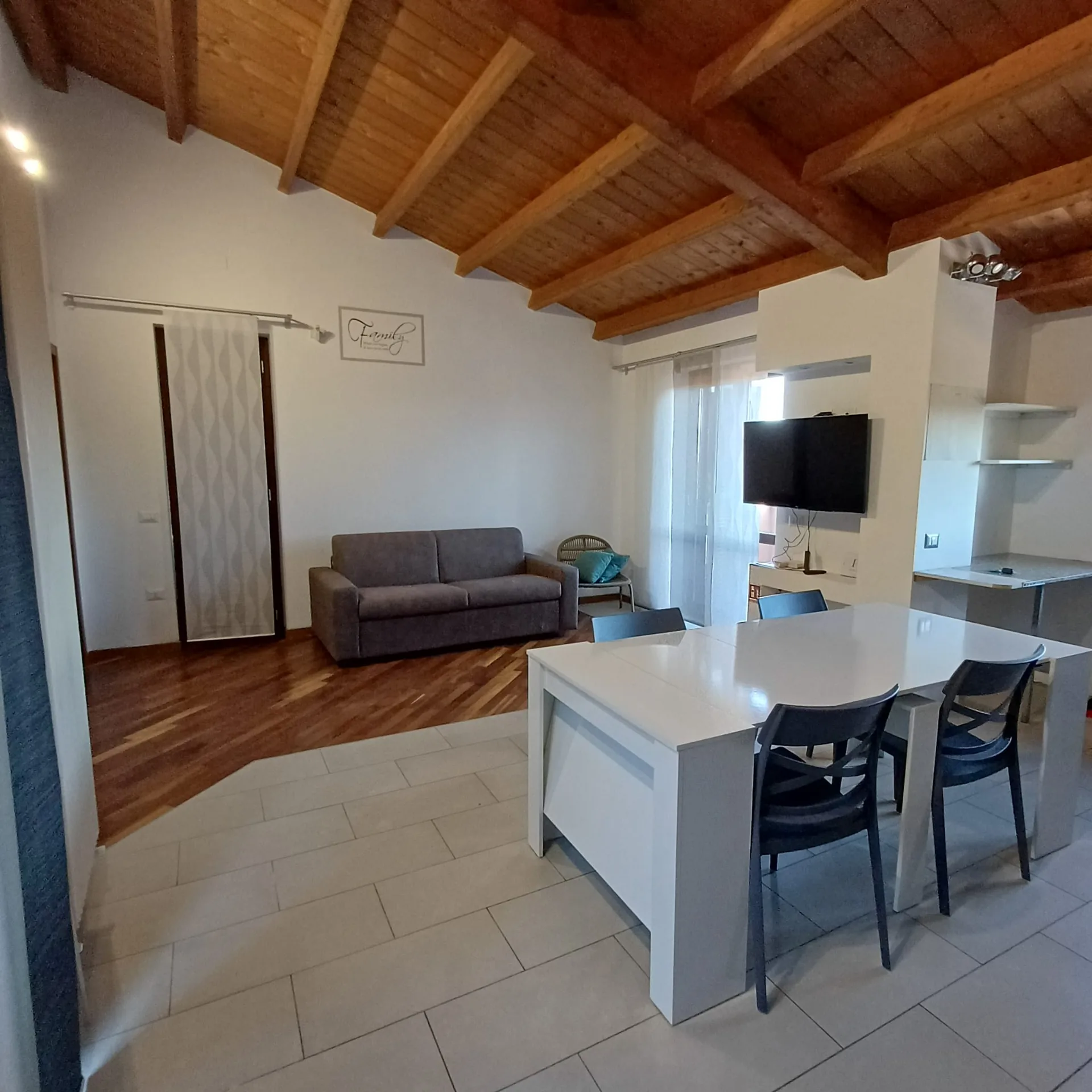Soggiorno luminoso di PN HOUSE con cucina, tavolo e soffitto con travi in legno